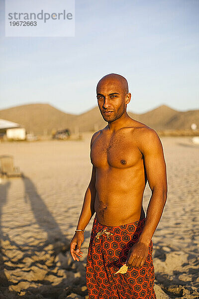 Ein Porträt eines Mannes am Strand ohne Hemd.