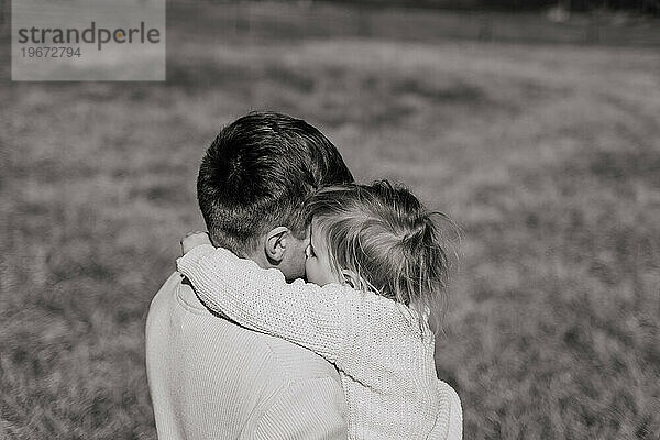 Ein Mann umarmt ein kleines Kind fest auf einem trockenen Feld  Rückansicht  Nahaufnahme