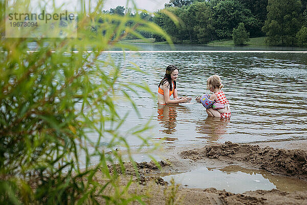 Zwei Mädchen spielen zusammen am Seeufer im Sand