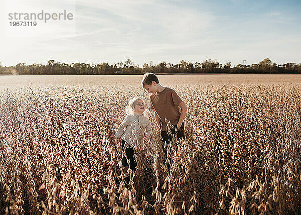Geschwister schauen sich im Herbst im goldenen Feld liebevoll an