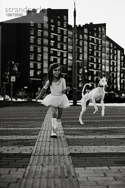 Mädchen mit weißem Hund auf einem Spaziergang in der Stadt.