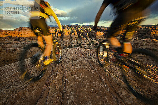 Ein Paar beim Mountainbiken auf einer Felsformation in der Nähe von Moab  Utah. (Bewegungsunschärfe)