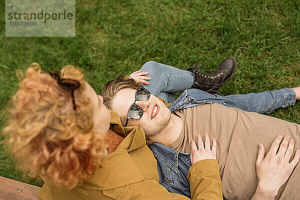Glückliches Paar entspannt sich an einem sonnigen Tag auf der Wiese im Park