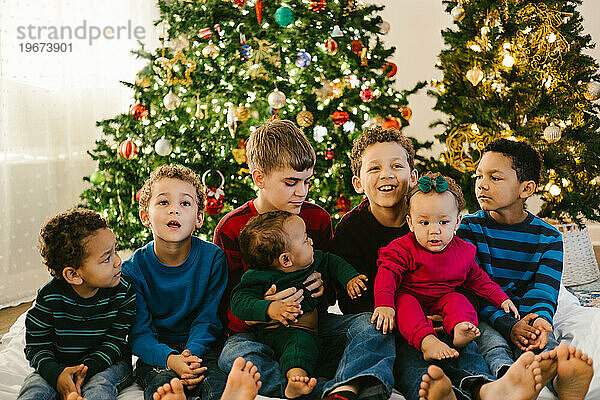 Vielfältige Großfamilie mit vielen Kindern vor dem Weihnachtsbaum