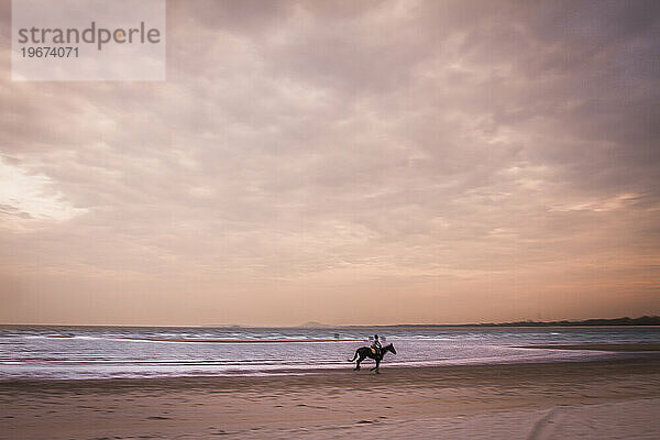 Mann reitet auf einem Pferd am Strand.
