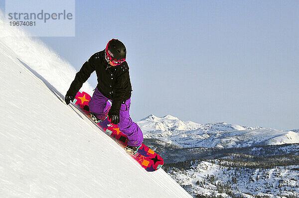 Eine Frau beim Snowboarden auf einem steilen Abhang in einem Bergresort in der Nähe von South Lake Tahoe  Kalifornien.