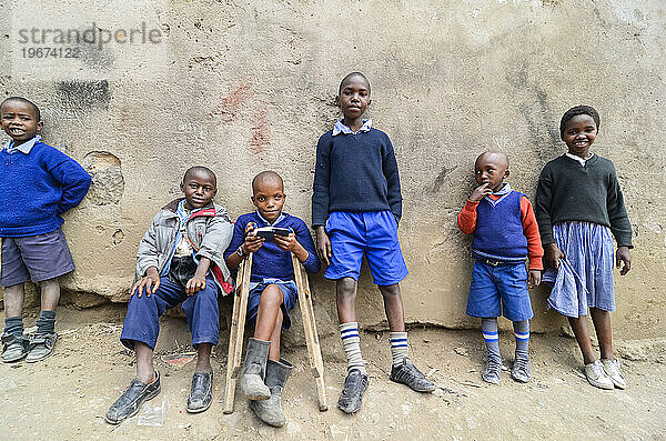 Gruppe junger Jungen  die sich an eine Wand lehnen  Kenia  Afrika