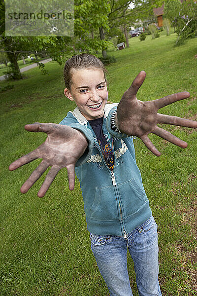 Ein Mädchen zeigt der Kamera ihre schmutzigen Hände.