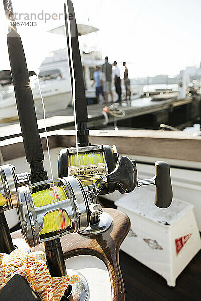 Ein Blick auf Angelruten am Dock  im Hintergrund spricht ein Fischer.