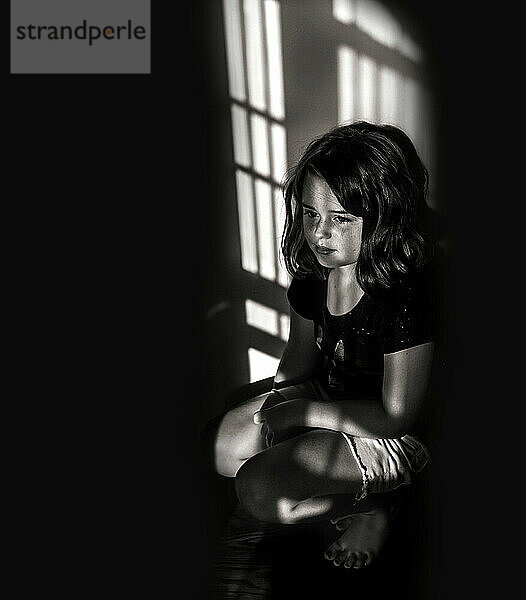 Schönes kleines Mädchen  das im Schatten sitzt