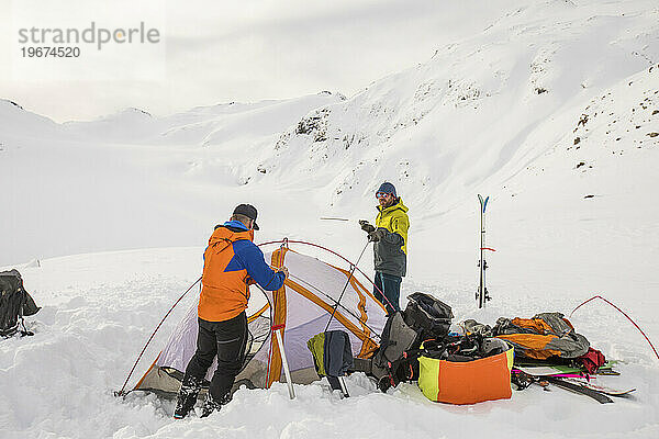 Zwei Männer arbeiten zusammen und bauen ein 4-Jahreszeiten-Zelt auf einem Gletscher auf