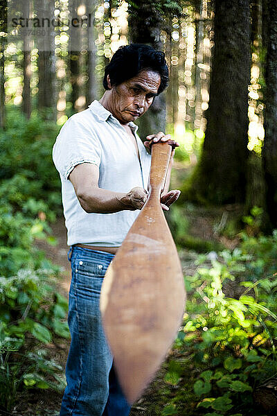 Ein auf Vancouver Island geborener Mann begutachtet sein handgeschnitztes Paddel.