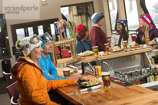 Eine Gruppe von Freunden genießt beim Après-Ski im Winter in Kirkwood  Kalifornien  eine Runde Bier und Essen an der Bar im Kirkwood Mountain Resort.