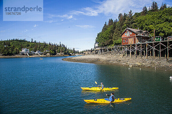 Zwei Kajakfahrer paddeln durch die ruhigen Gewässer in der Kleinstadt Halibut Cove  Alaska.