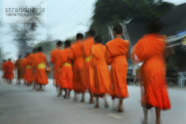 Buddhistische Mönche gehen im Morgengrauen in einer Präzession und nehmen Almosen entgegen  Luong Probang  Laos (Weichzeichnung) (Bewegungsunschärfe)