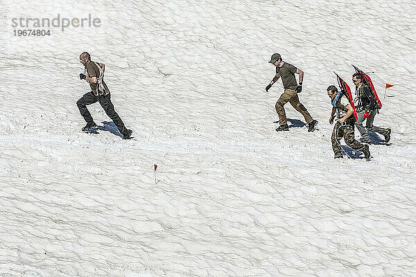 Gruppe von Menschen  die zu einer Rettungsstelle im Schnee gehen. Dies ist ein Training zur Lawinenbergung mit dem Schlitten.
