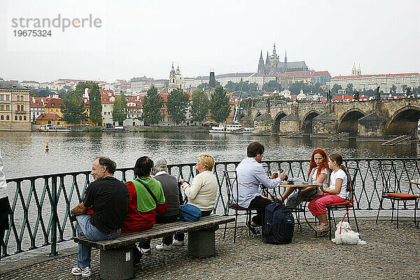 Menschen sitzen in einem Café mit Blick auf die Karlsbrücke und die Burg  Prag  Tschechische Republik.