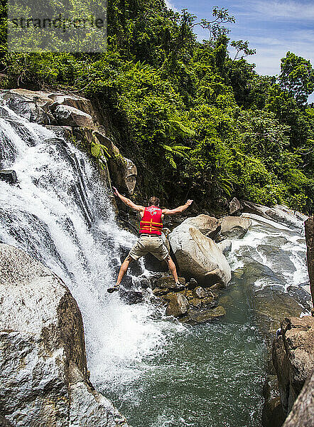 Ein Mann springt von einem hohen Felsen in den Wasserfall  Puerto Rico