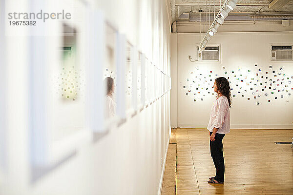 Eine junge Frau genießt eine Kunstausstellung in einer Galerie.