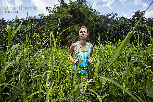 Eine junge Frau wandert an einem sonnigen Tag auf Abenteuerreise durch den Dschungel von Puerto Rico.