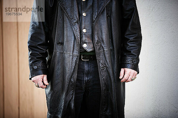 Ausgeschnittene Vorderansicht eines Mannes  der eine lange schwarze Lederjacke trägt.