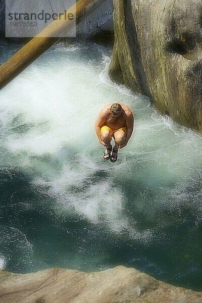 Verschwommene Bewegung eines Mannes  der bei Moss Glen Falls in Vermont in den Fluss springt.