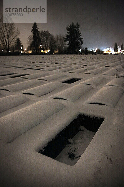 Ein einsames  leeres Friedhofsgrundstück im Schnee in Washington bei Nacht.