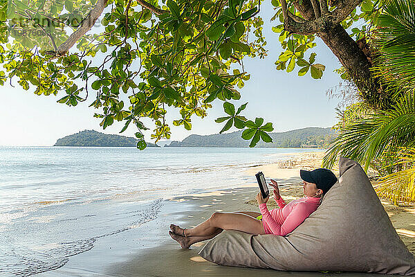 „Digital Escape  Frau entspannt sich mit einem E-Book am Strand“