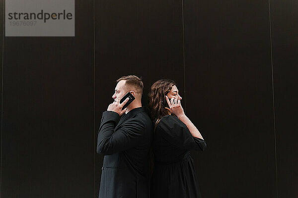 Ein Mädchen und ein Mann telefonieren in Schwarz auf schwarzem Hintergrund