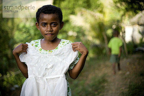 Ein Porträt eines jungen Mädchens aus Fidschi  das beim Anziehen ihr Lieblingsstück in der Hand hält.