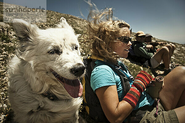 Ein Hund und drei Personen sitzen am Hang eines Berges in La Sals  Utah.