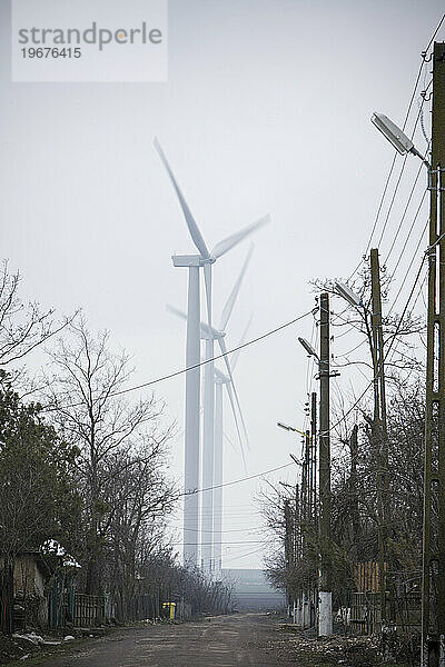 Eine unbefestigte Straße in der kleinen rumänischen Stadt Fantanele mit Windkraftanlagen von Europas größtem Windpark FÃ?Â¢ntÃ?Â¢nele-Cogealac.