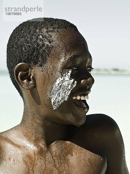 Ein kleiner Einheimischer vergnügt sich an einem sonnigen Tag am Strand von Turks- und Caicosinseln im Sand.