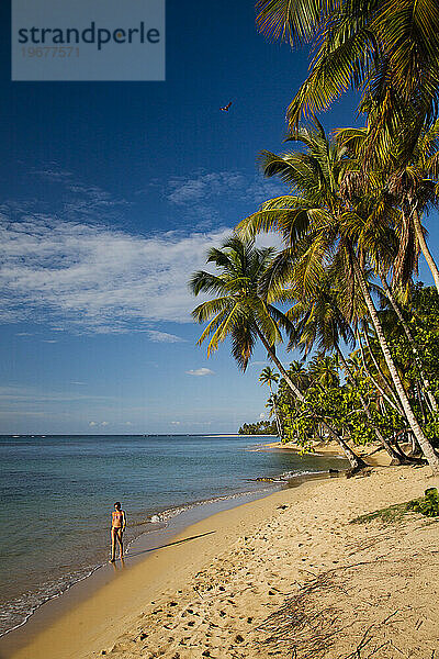 Eine Frau genießt einen gemütlichen Spaziergang an einem einsamen Strand in Las Terrenas.