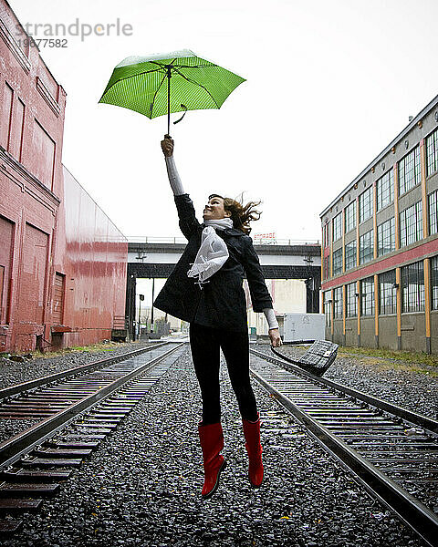 Eine Frau in der Luft  die einen Regenschirm hält.