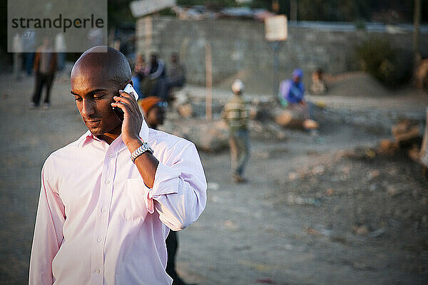 Ein junger äthiopischer Mann telefoniert auf einer staubigen Straße in Äthiopien.