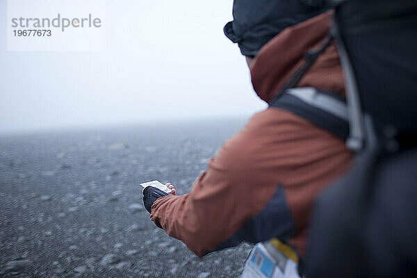 Wanderer liest Kompass im Hochland von Island