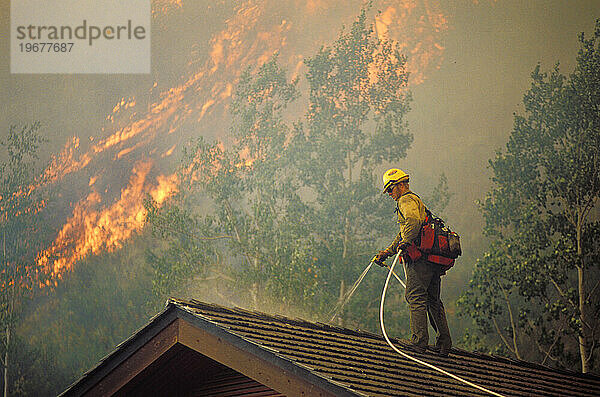 Feuerwehrmann schützt Haus vor Feuer.