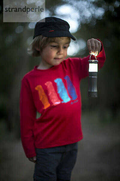 Ein kleiner Junge und sein Licht  in einem dunklen Wald.