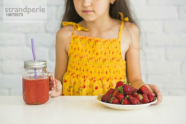 Close up Mädchen hält Teller Erdbeeren Smoothies Glas