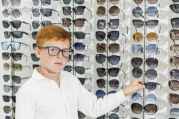 Unschuldiger Junge schaut Kamera weiß haltend Brillenoptik speichern