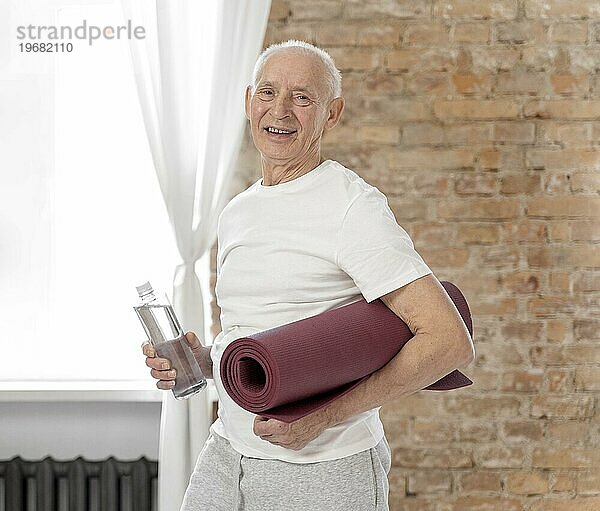 Mittlere Aufnahme älterer Mann mit Yogamatte