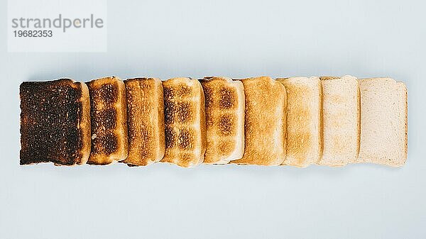 Draufsicht Brotscheiben verschiedene Stadien Toasten angeordnet Reihe weißem Hintergrund