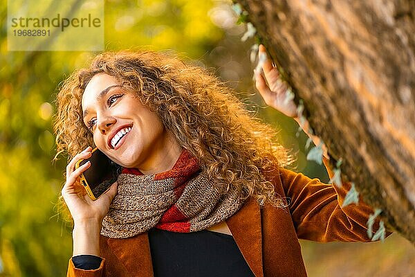 Schöne Frau im Gespräch mit dem Handy in einem Park im Herbst