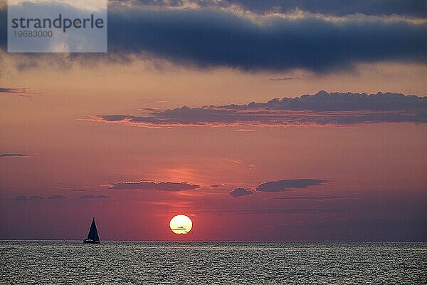 Sonnenaufgang über Cap Corse im Ligurischen Meer mit einem Segelboot am Horizont. Haute Corse  Insel Korsika  Frankreich  Europa