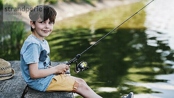 Portrait glücklicher Junge beim Fischen am See