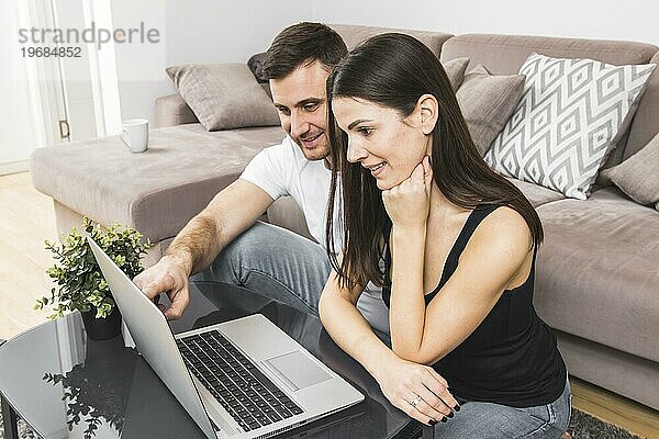Lächelndes junges Paar benutzt Laptop zu Hause