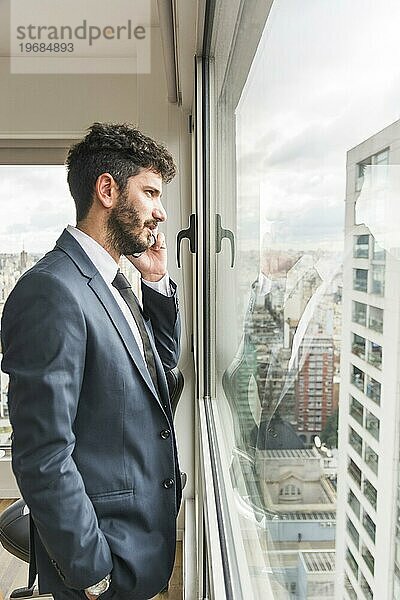 Seitenansicht Geschäftsmann steht in der Nähe von Büro Fenster sprechen Handy