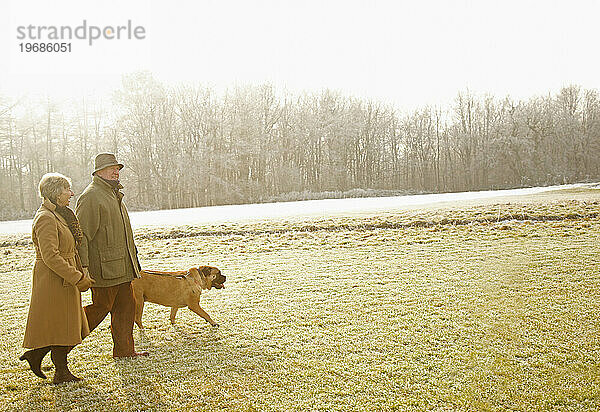 Profil eines älteren Paares  das mit einem Hund in einem Park spazieren geht
