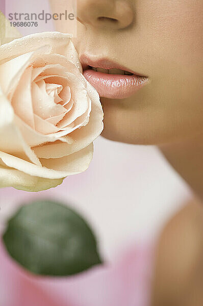 Extreme Nahaufnahme einer jungen Frau  die eine rosa Rose inhaliert